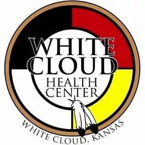 Logo of the White Cloud Health Center, featuring a medicine wheel in red, black, white, and yellow, with two feathers at the bottom and the text "White Cloud Health Center, White Cloud, Kansas."