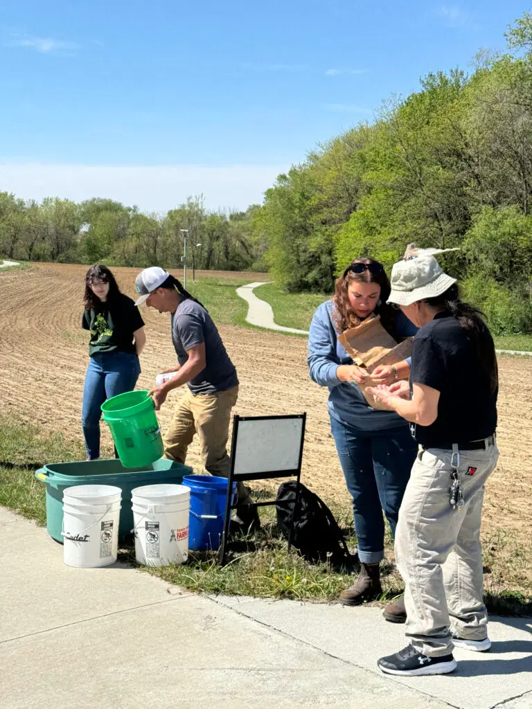 Kate Kyser, Brett Ramey, Amy June, and Reuben Kent examine the seed and divide it up to be hand-spread.