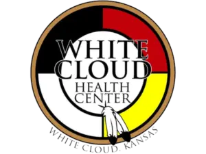 Logo of the White Cloud Health Center, featuring a medicine wheel in red, black, white, and yellow, with two feathers at the bottom and the text "White Cloud Health Center, White Cloud, Kansas."